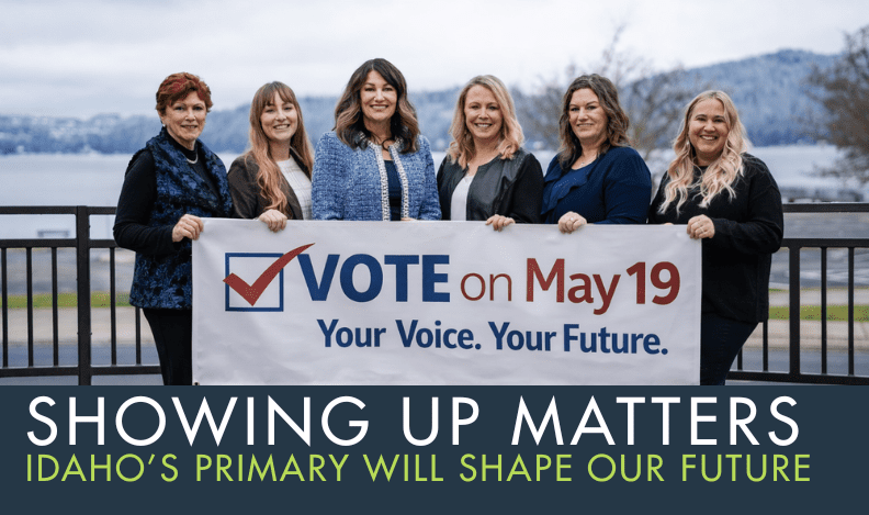 Coeur d’Alene Regional Chamber staff holding a banner that reads “Vote on May 19 – Your Voice. Your Future.” along the waterfront in Kootenai County